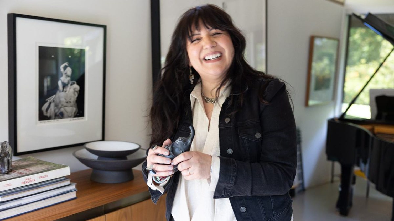 Frances Méndez laughing, holding a camera, in a sunlit room